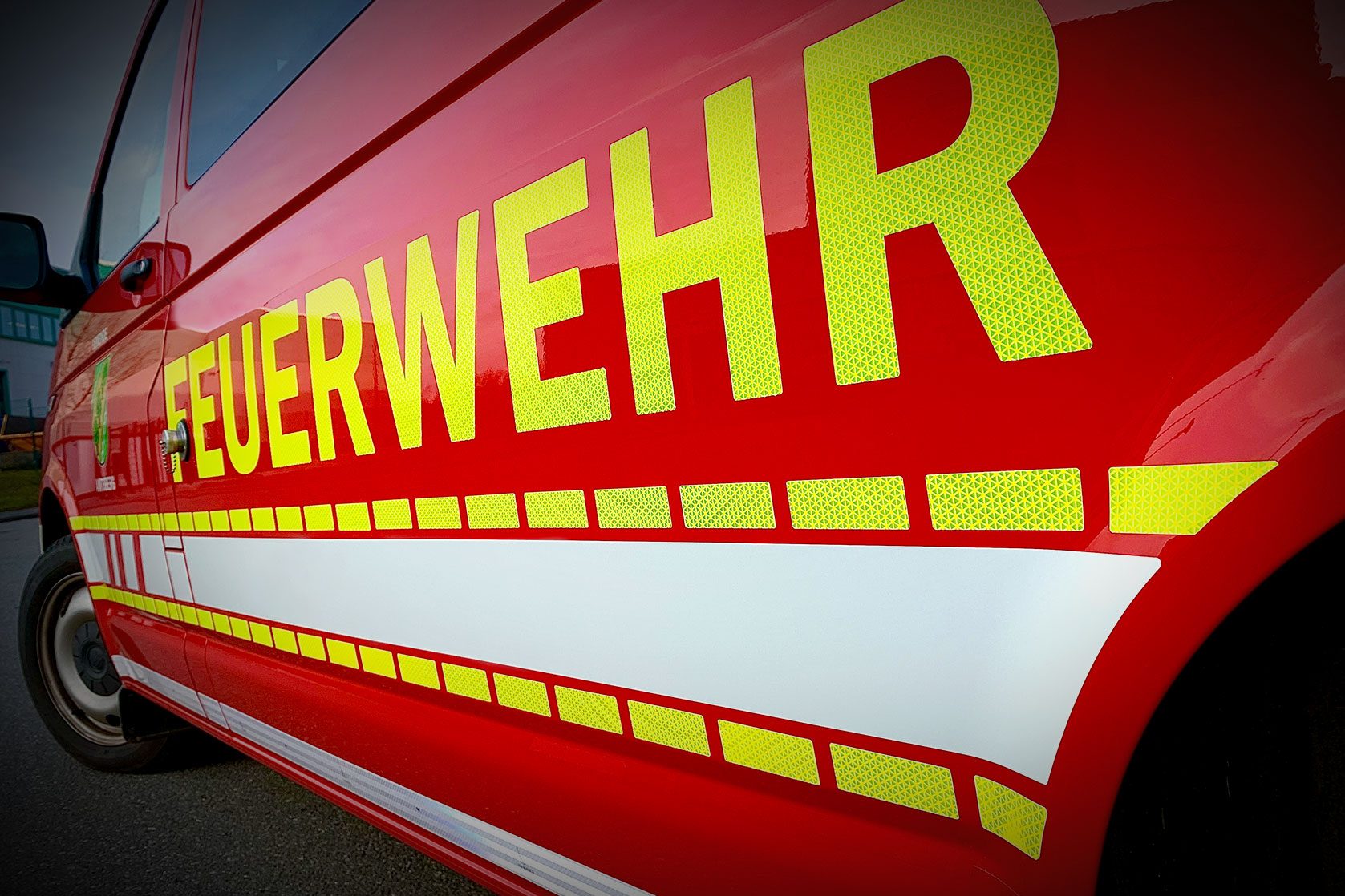 Fahrzeugbeschriftung „FEUERWEHR“ mit reflektierender Folie auf rotem Einsatzfahrzeug