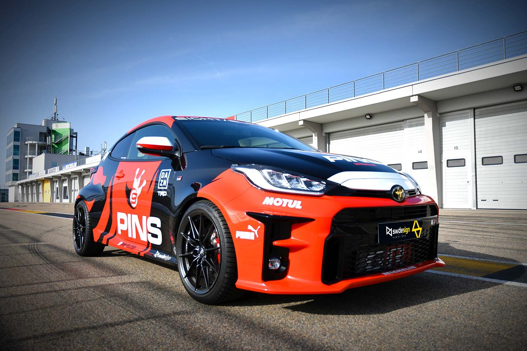 Toyota GR Yaris mit Motorsport-Folierung im 9 PINS-Design auf einer Rennstrecke.