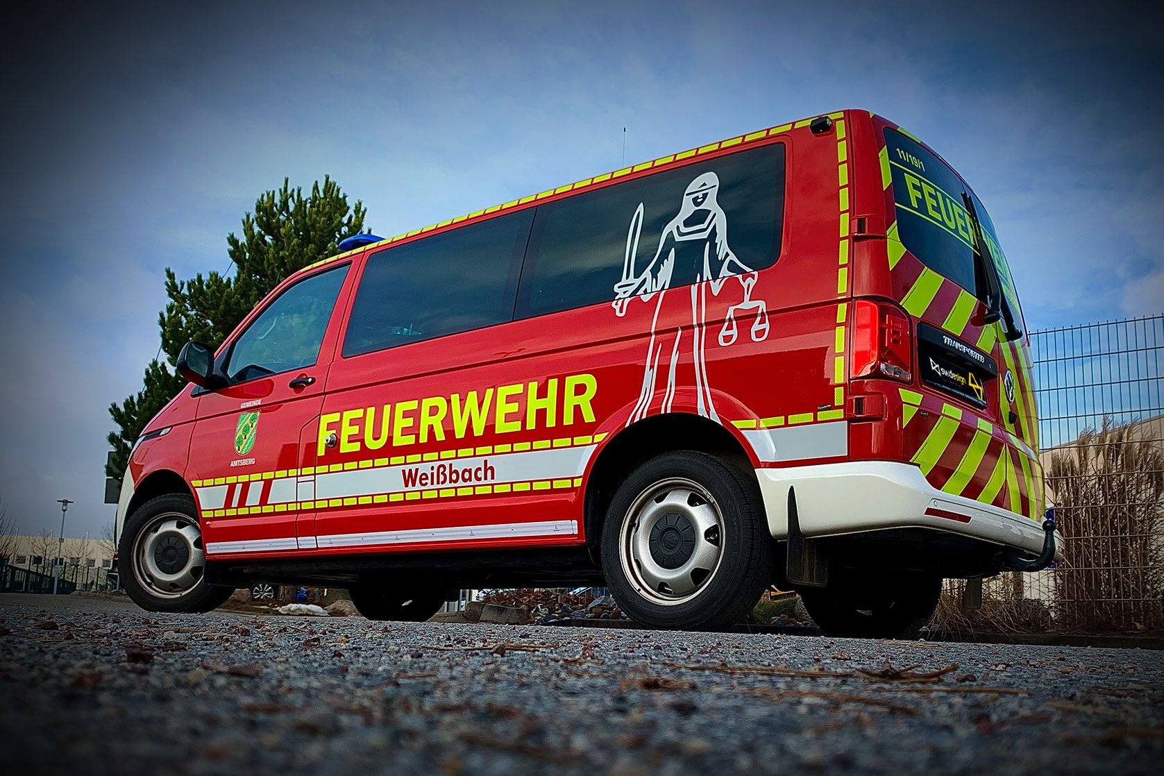 Roter VW-Bus mit Feuerwehrbeschriftung Weißbach und Justitia-Grafik