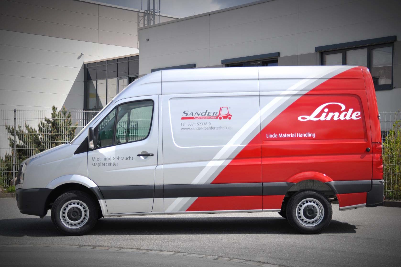 Transporter mit Firmenbranding von Sander Fördertechnik und Linde Material Handling auf grauem Hintergrund.