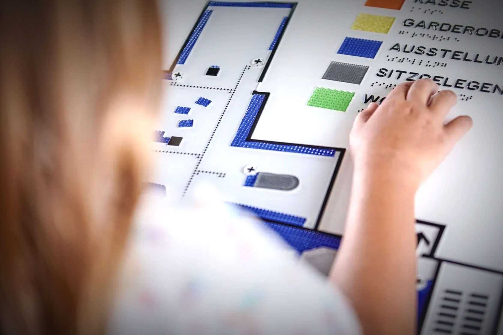 Kind ertastet barrierefreien Gebäudeplan mit Brailleschrift