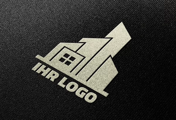 Einfarbiges Logo in Weiß auf schwarzem Stoff, Nahaufnahme mit klaren Konturen.