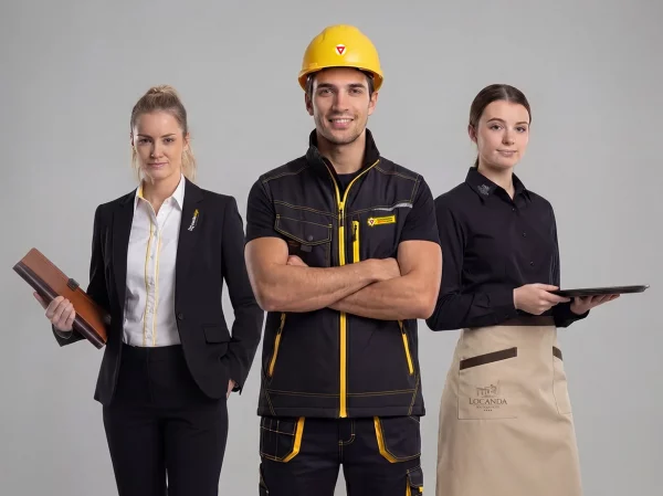 Drei Personen in Corporate Wear: Handwerker mit gelbem Helm und Arbeitskleidung sowie zwei Mitarbeiterinnen in Business- und Service-Outfit.