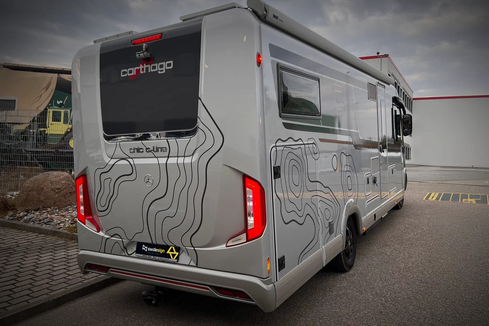 Carthago Wohnmobil mit individueller Designfolierung im Topografie-Look auf Heck und Seitenflächen.