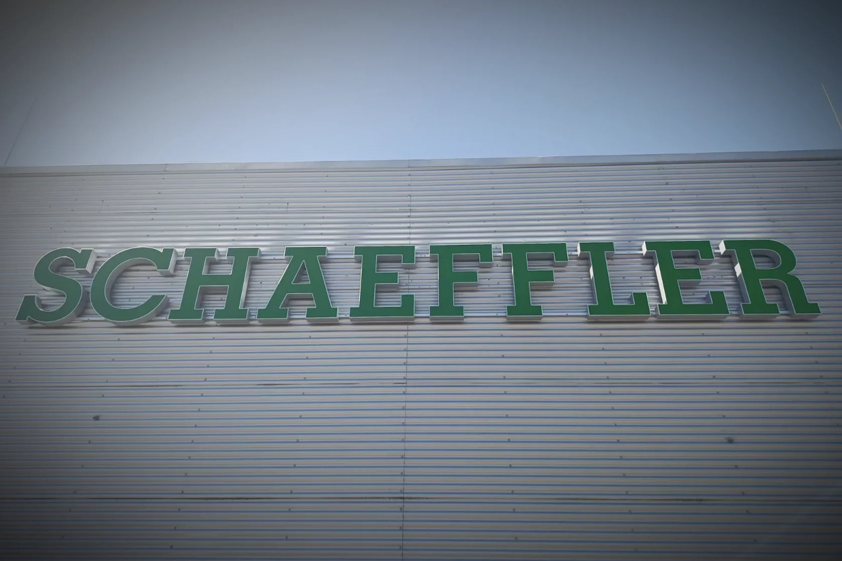 Großformatige 3D-Leuchtbuchstaben mit Schaeffler-Schriftzug an einer Industriehallenfassade.