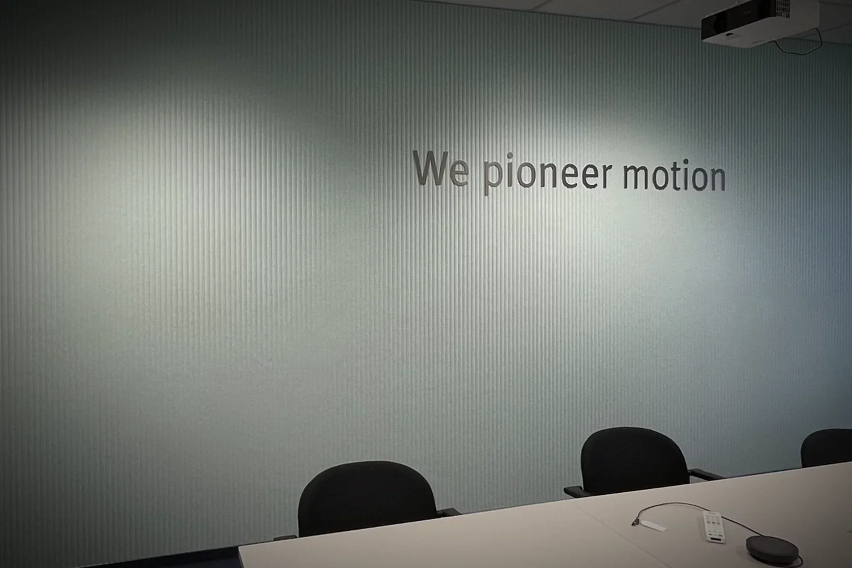 Moderne Wandbeschriftung mit 3D-Schriftzug „We pioneer motion“ im Konferenzraum von Schaeffler.