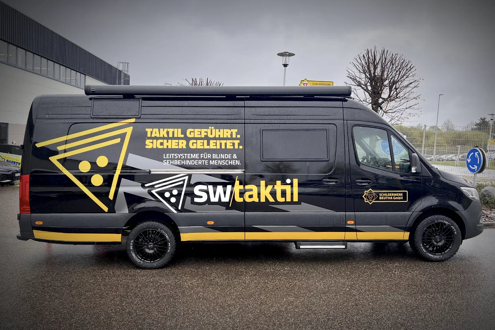 Schwarzer Mercedes Sprinter mit hochwertiger Fahrzeugfolierung für Leitsysteme und Barrierefreiheit.